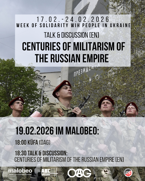 military parade from russain soldiers. in the background at a house is a huge propaganda banner with a z on it